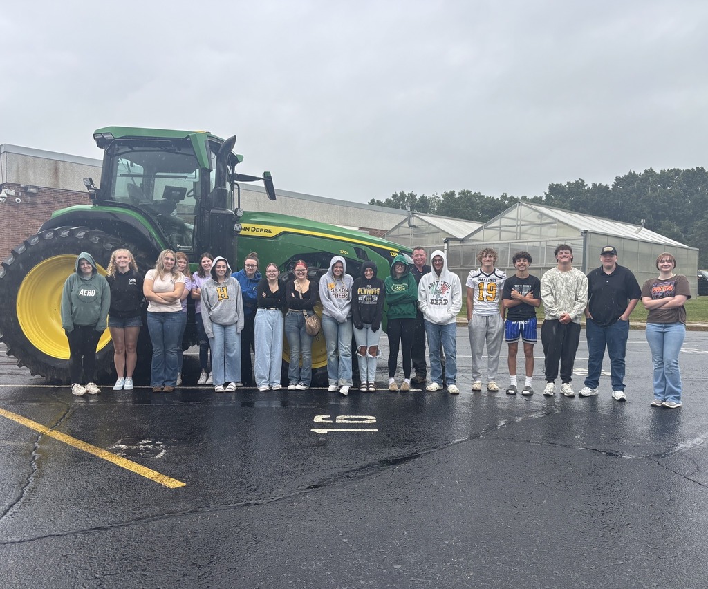 Students stand for a photo in front of a tractor.