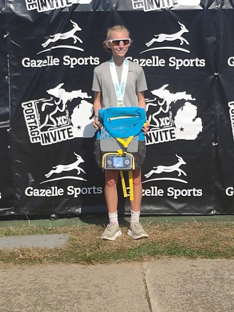 Caroline Randall stands in front of a Portage Invite banner with a medal around her neck.