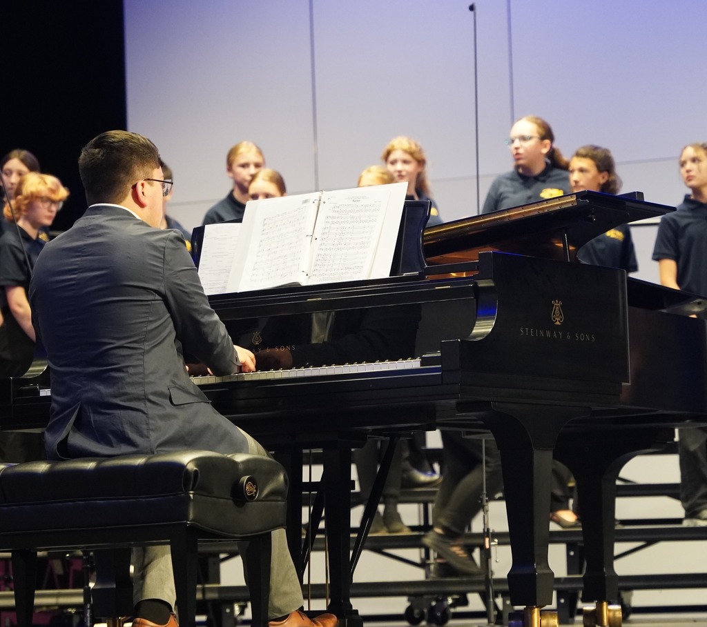 A photo depicting the back of a pianist who is accompanying the Hastings Middle School choir