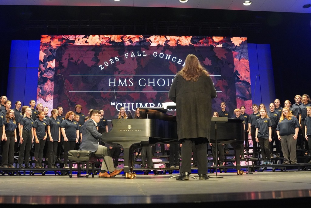 Mrs. Byykkonen directing a choir on stage.