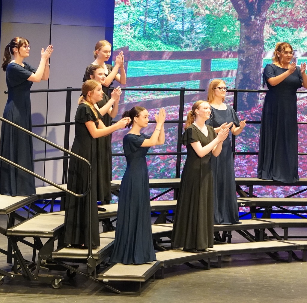 Female choir singers clapping to the beat and smiling