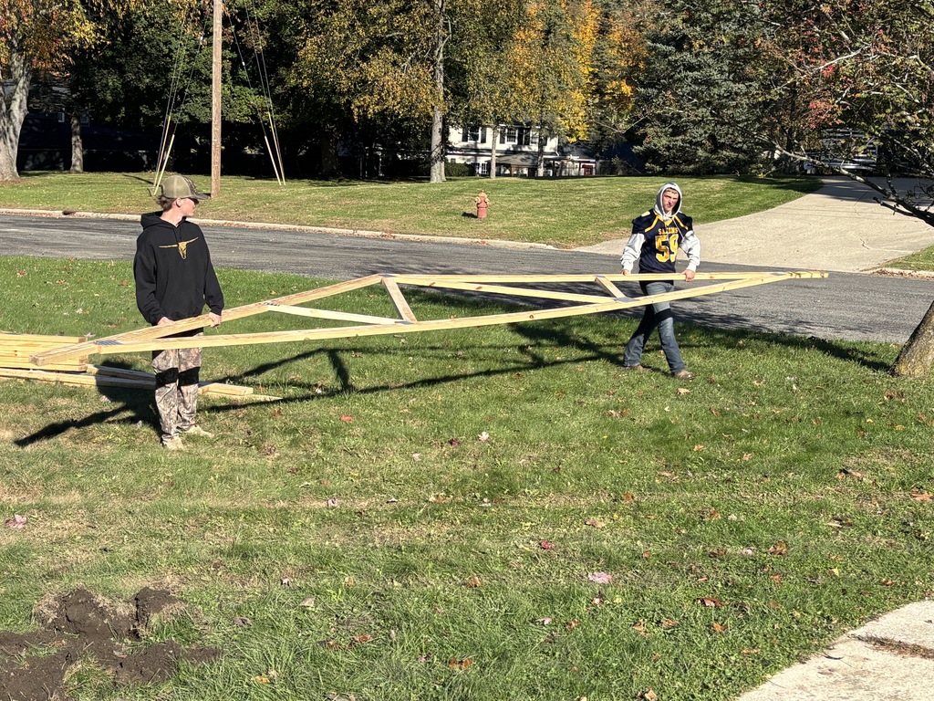 Two Hastings High School students carry a truss on the job site.