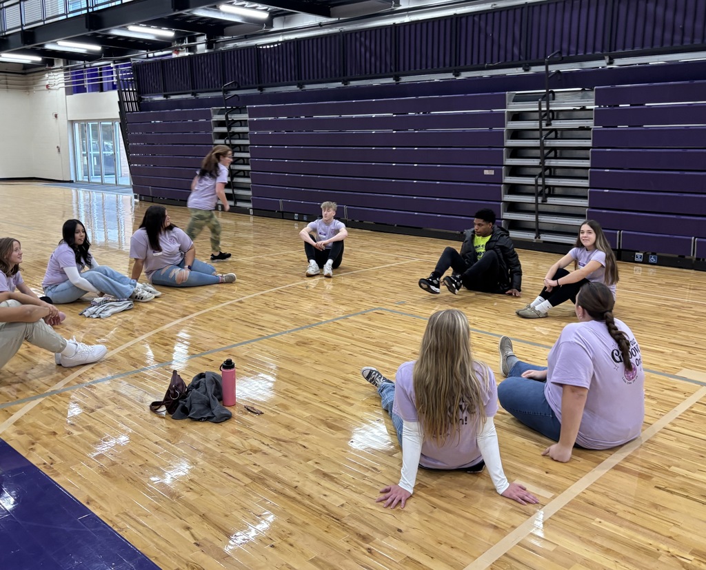 Hastings High School Link Crew leaders sit in a circle on a gym floor.