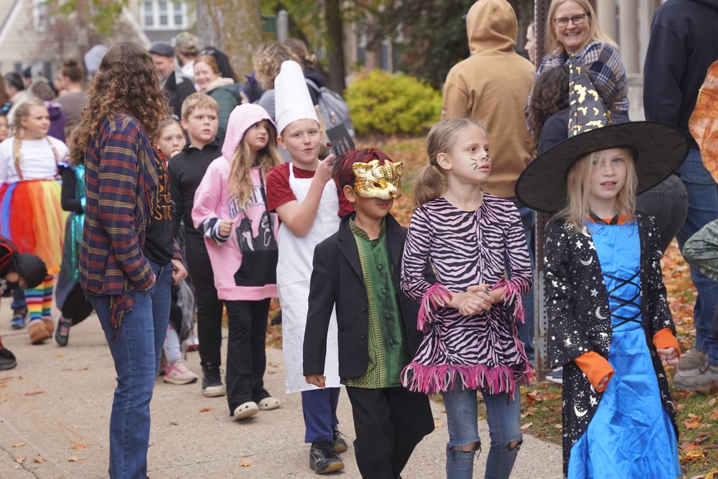 Central Elementary students walking through a tunnel of parents during the Halloween parade.