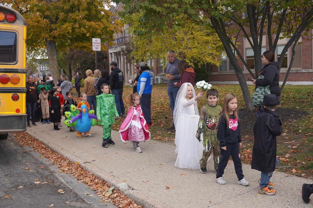 Central Elementary students walking through a tunnel of parents during the Halloween parade.