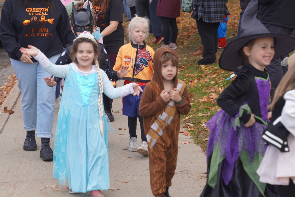 Central Elementary students walking through a tunnel of parents during the Halloween parade.