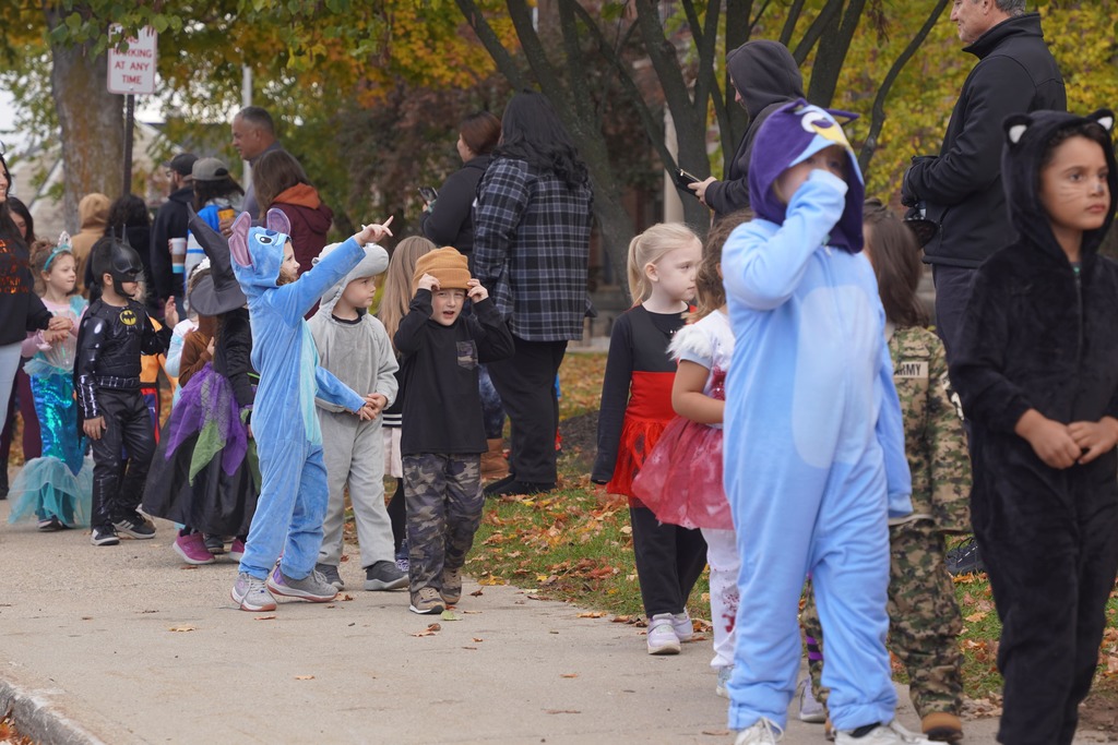 Central Elementary students walking through a tunnel of parents during the Halloween parade.