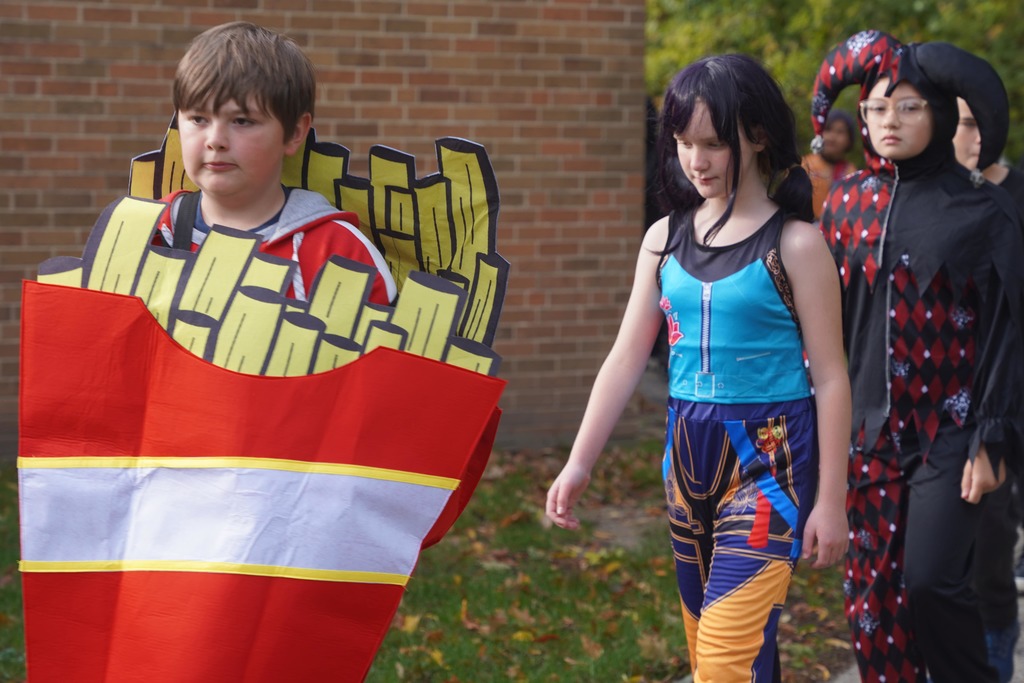 Southeastern Elementary students walking in their Halloween parade, surrounded by onlooking parents.
