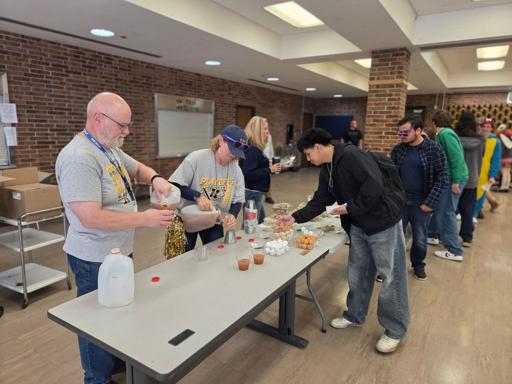 Students getting cider and donuts from a table during College Month celebration