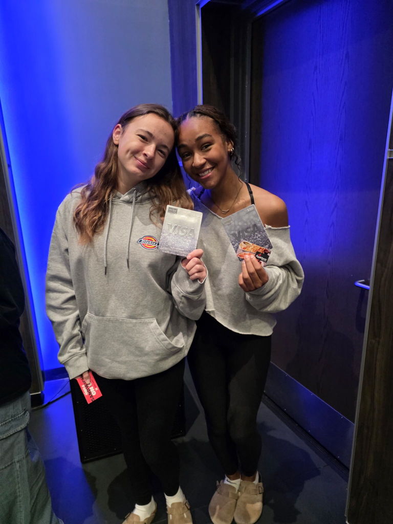 Two students holding up prizes they won in a drawing.