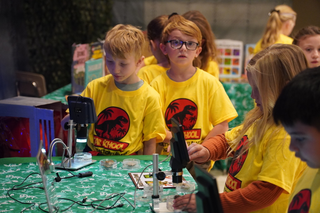 Kids line up by a microscope