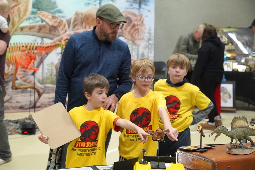 Students eagerly point as a display of dinosaur materials.