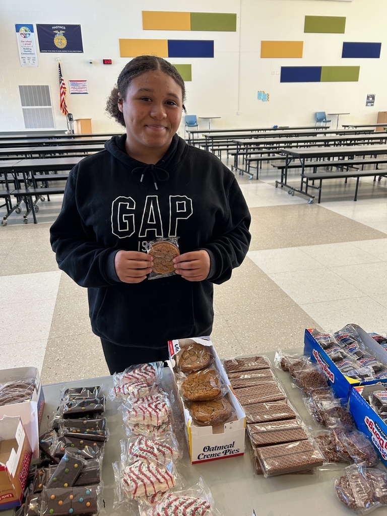 A student standing behind a table filled with snack cakes