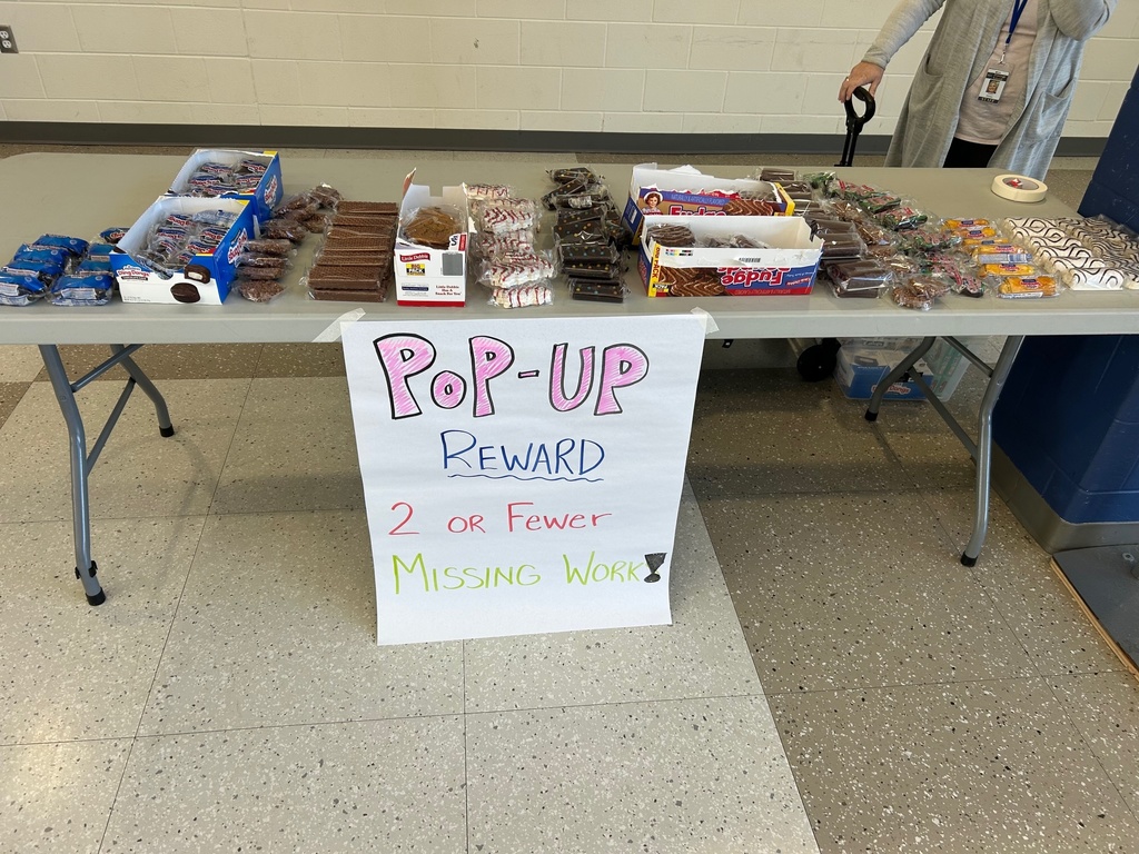 A table littered with snack cakes with a sign that says "Pop-Up Reward"