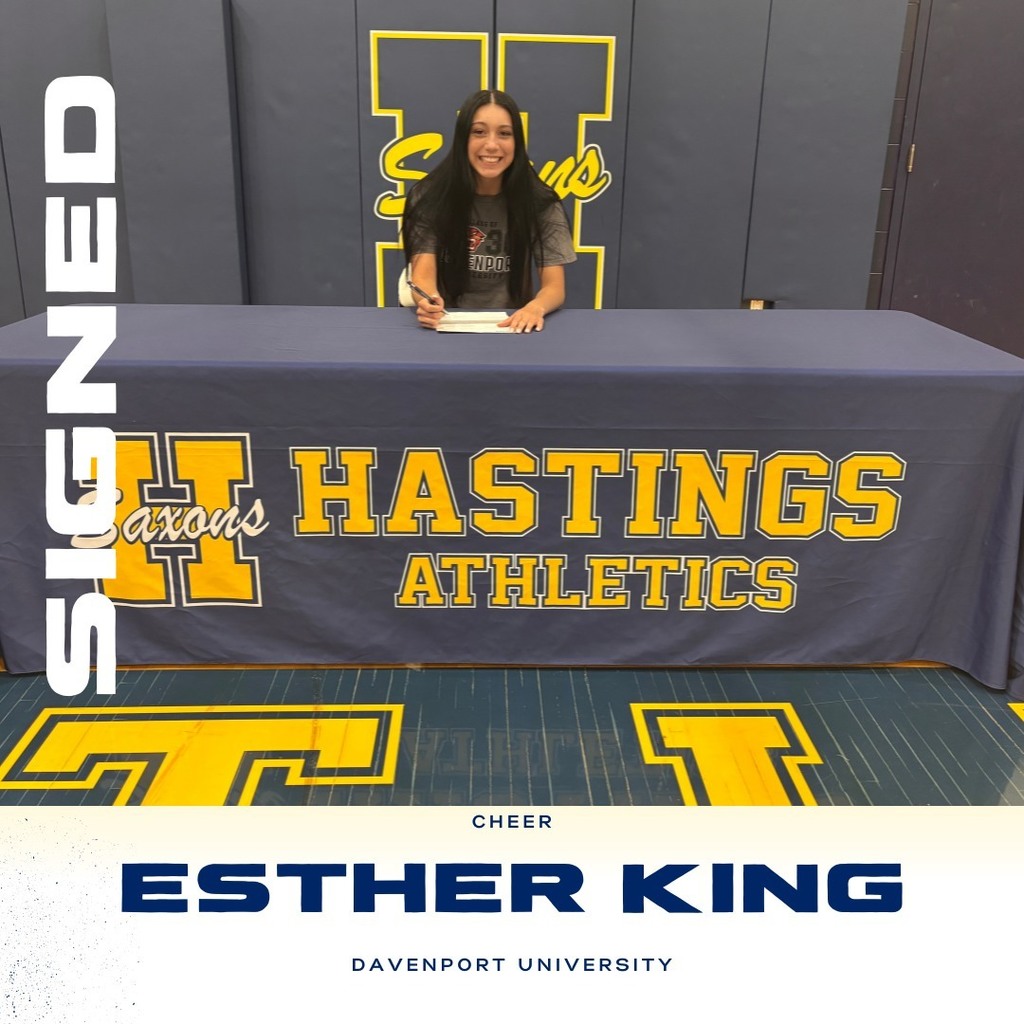 esther king sits behind a table with a paper in front of her ready to sign with an ink pen