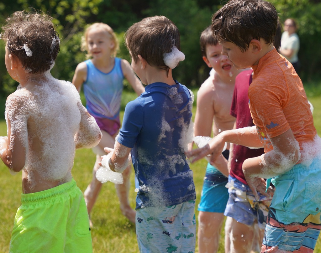 Kids play in foam and slide down a large tarp that is placed over a hill