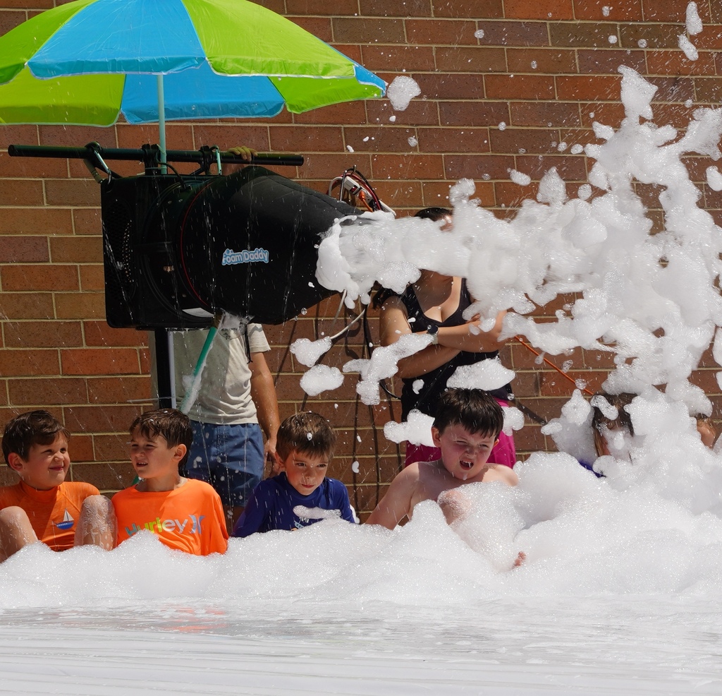 Kids play in foam and slide down a large tarp that is placed over a hill