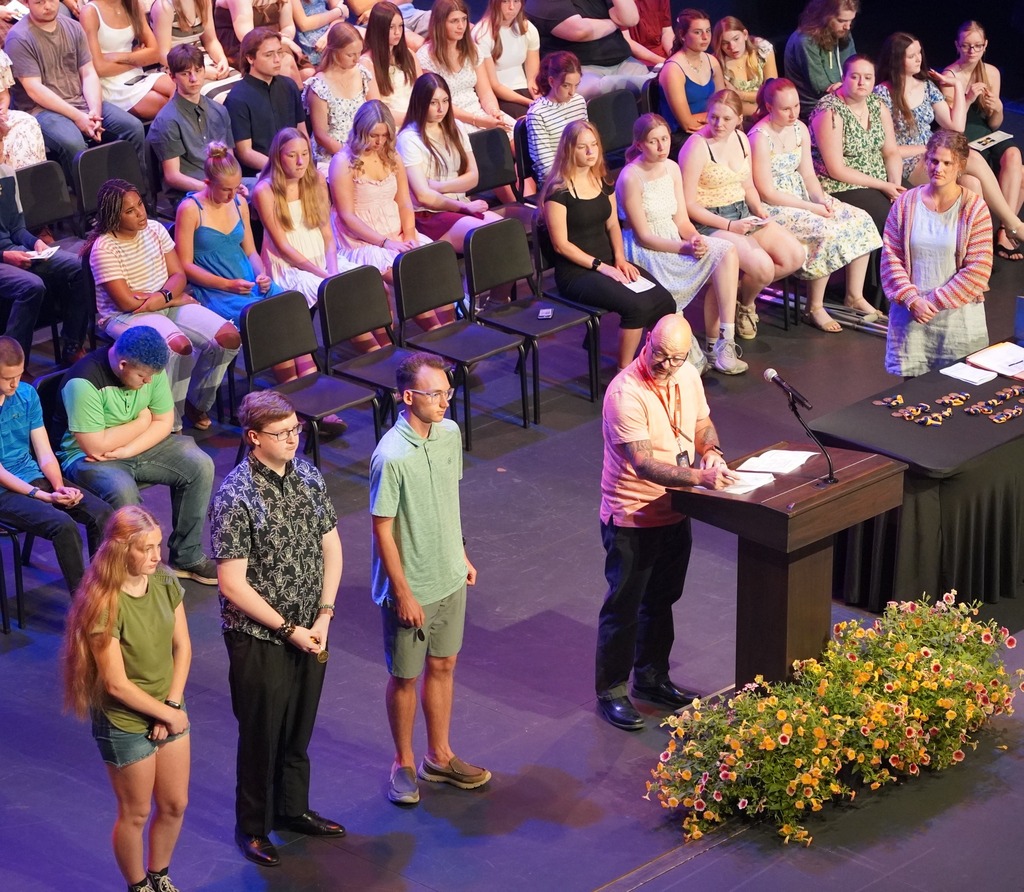 Students seated on stage and speakers present at HHS underclassmen honors night