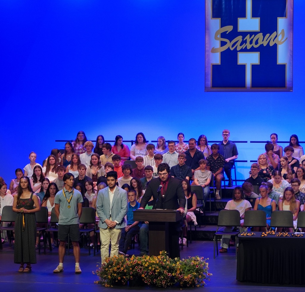 Students seated on stage and speakers present at HHS underclassmen honors night