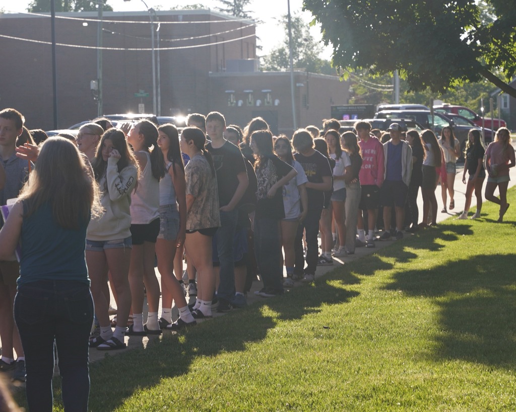 Teachers handing out plates of breakfast food to a long line of students