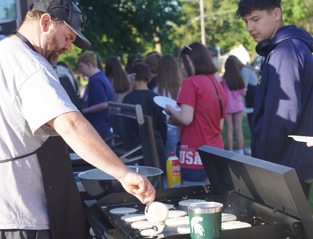 Teachers handing out plates of breakfast food to a long line of students