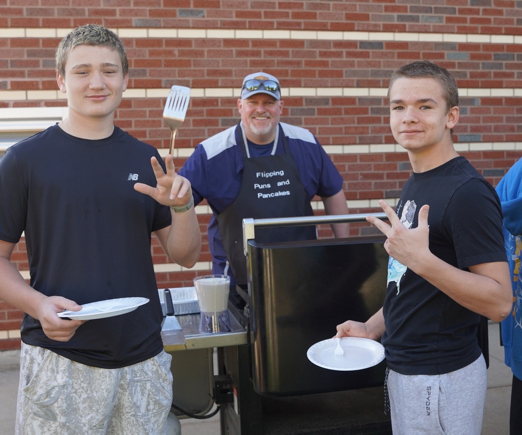 Teachers handing out plates of breakfast food to a long line of students