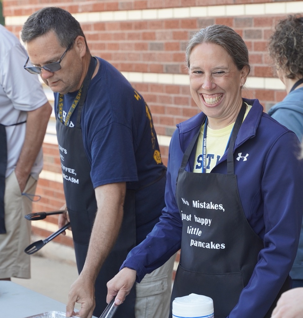 Teachers handing out plates of breakfast food to a long line of students