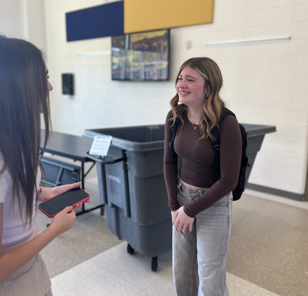 A young female student smiles through tears as she talks to a friend