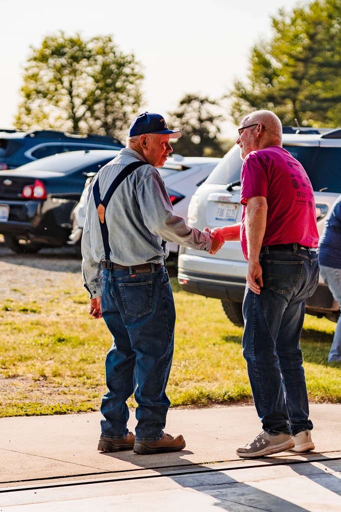 Two men exchange a handshake and smile