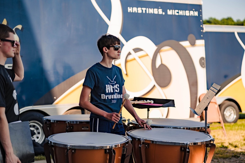 A male student stands behind large drums