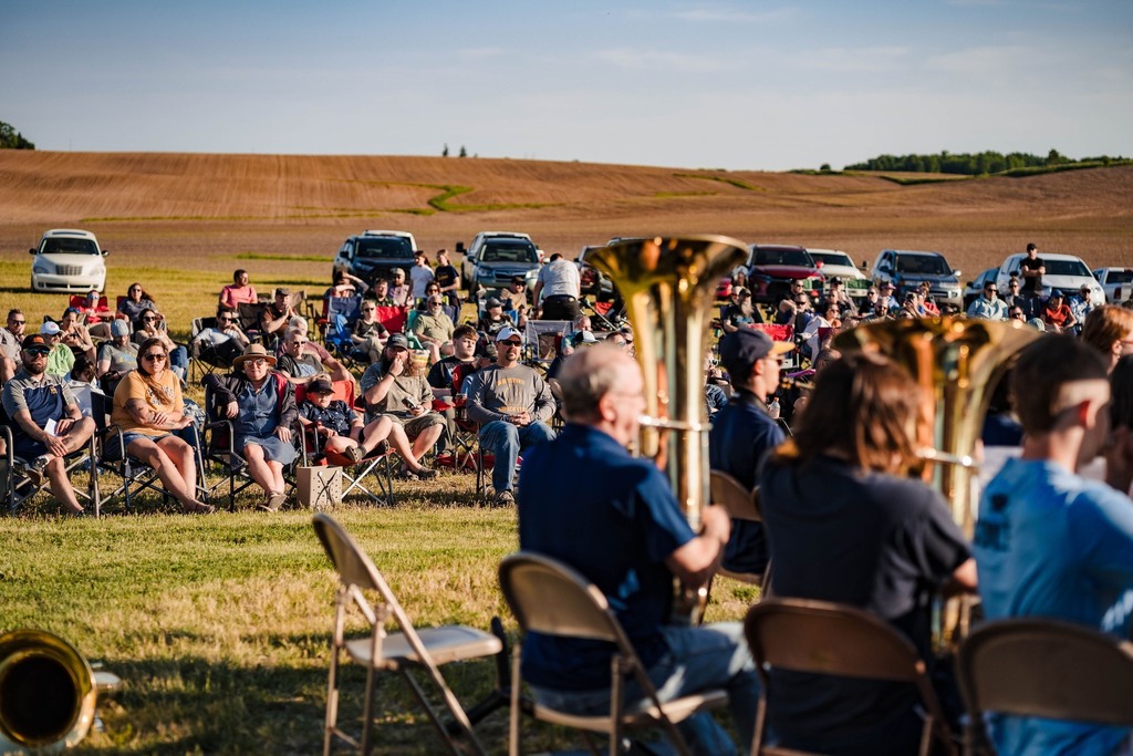 A school band performs in a large farm field