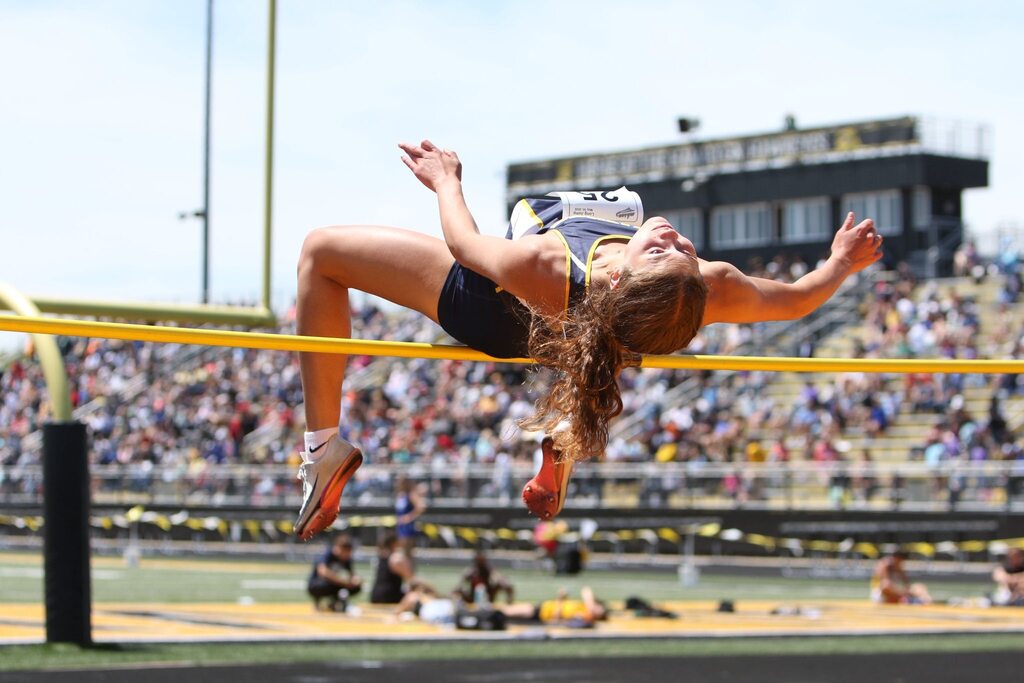 A female athlete launches herself over a high jump bar