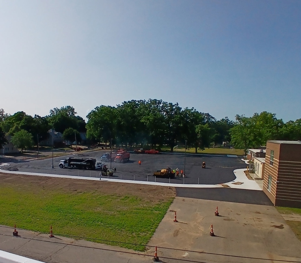 A far-away vantage point of crews working on a parking lot.