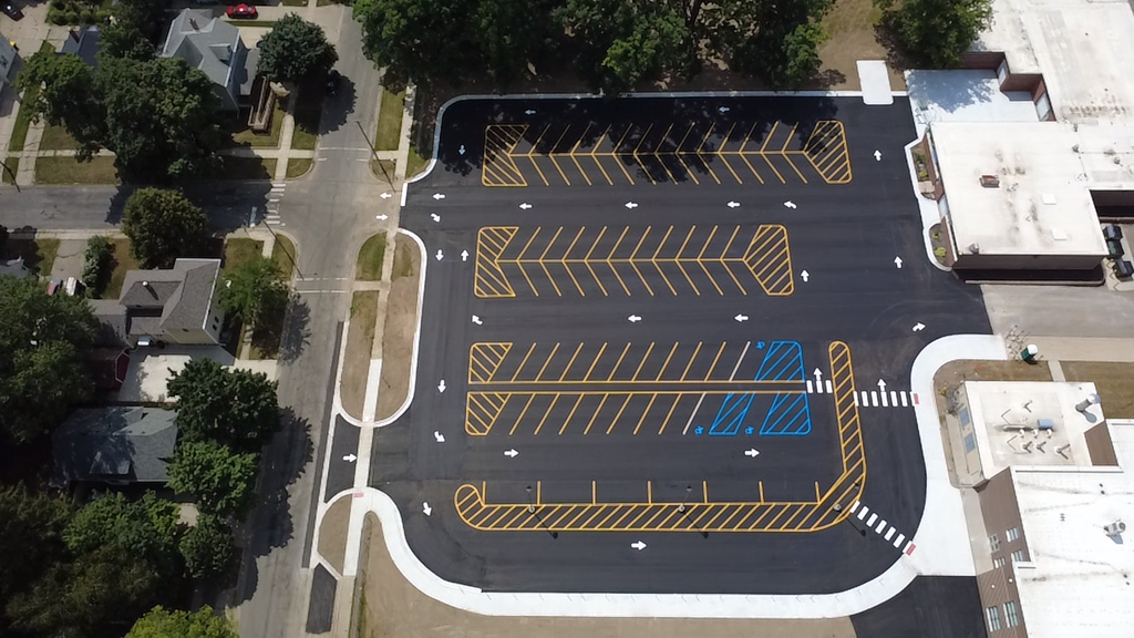 An aerial view of a parking lot that is freshly paved featuring bright yellow lines