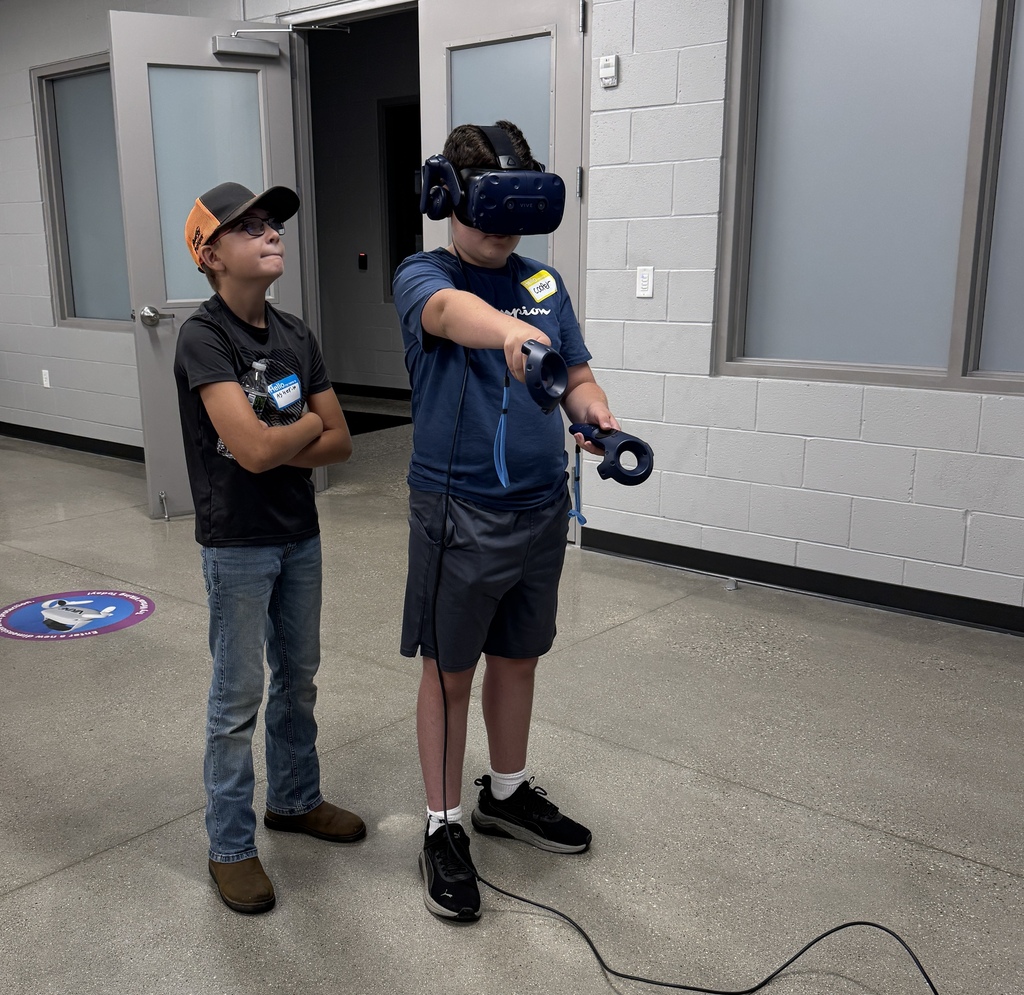 a boy is wearing virtual reality glasses and points a controller in front of him