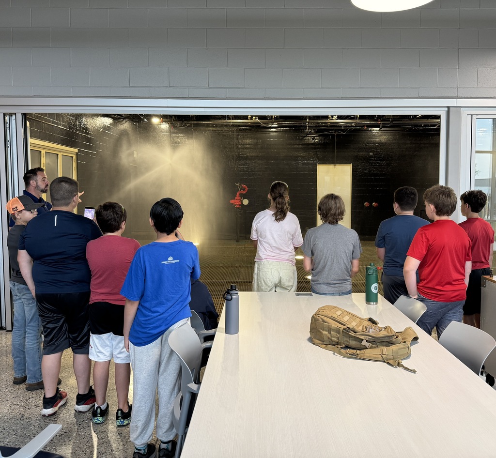 A group of students are looking inside of a room where they are testing our fire supression sprinklers.