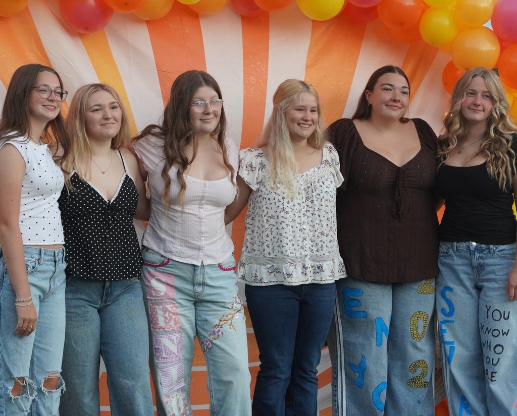 Six female students pose for a picture with a colorful background behind them.