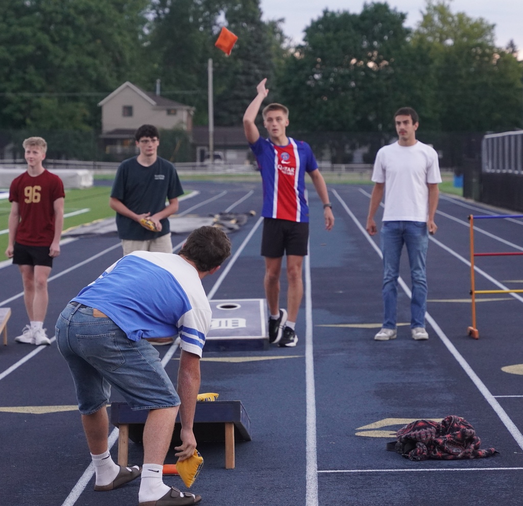 A high school boy tosses a bag up in the air during a game of cornhole
