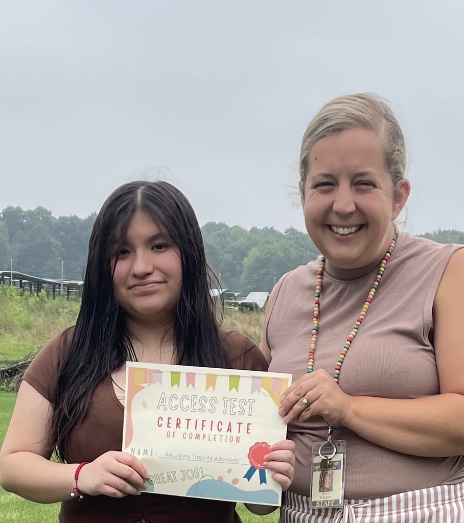 A girl and her teacher jointly hold a certificate that says "Access Test Certificat" on it