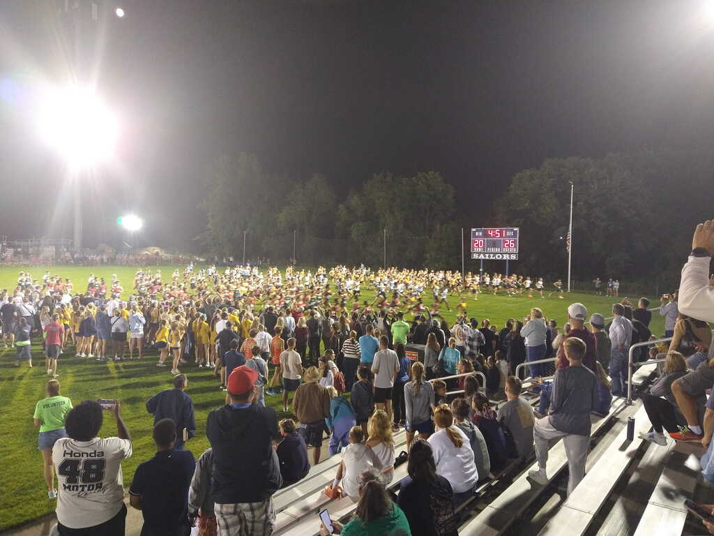 A aerial view of a massive cross country race, where hundreds of athletes are taking off from a starting line.