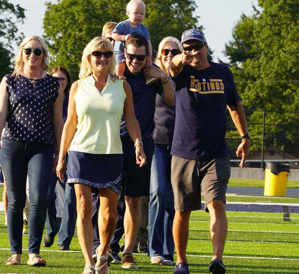 A group of people walks toward the camera. One man points directly at the photographer.
