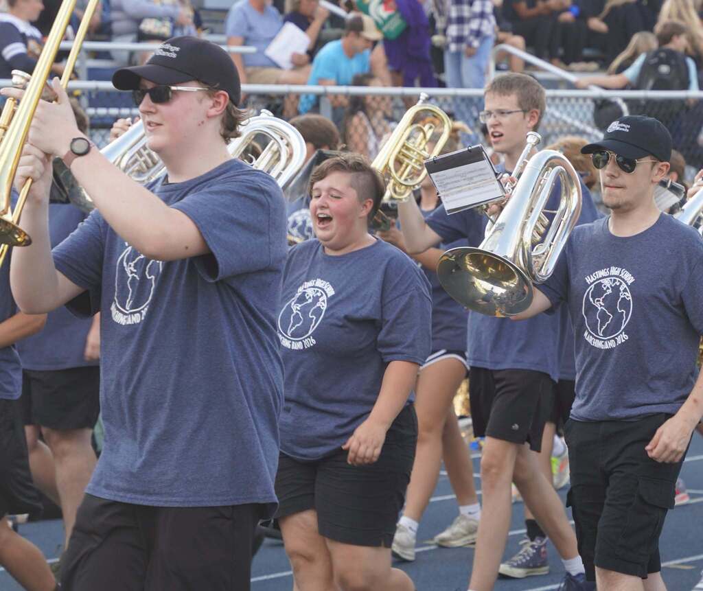 A close up of a group of marching band musicians. They are holding their instruments in front of them and yelling.