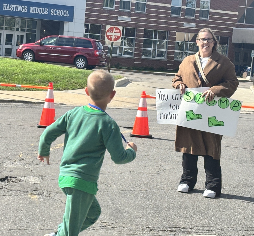 A boy in a green shirt looks at an adult who is holding an encouraging sign.