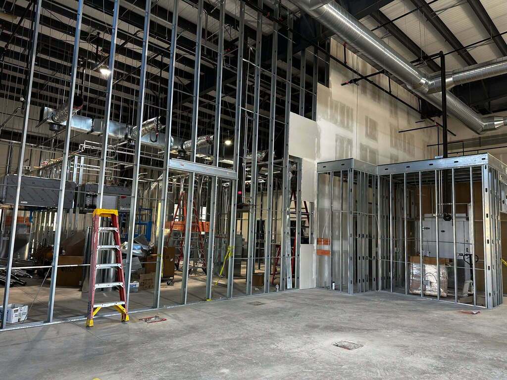 The look at a space that is under construction. Metal framing extends from the concrete floor to ceiling.