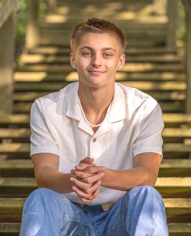 Male high school senior seated with a white button-down shirt on smiling