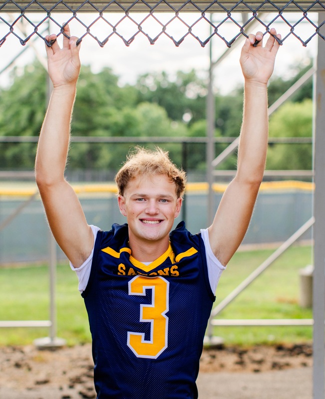 Male high school student wearing a football jersey with the number 3 on it smiling at the camera