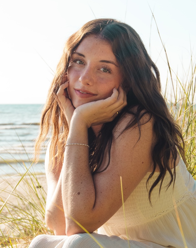 A female high school student seated with a beach scene behind her.