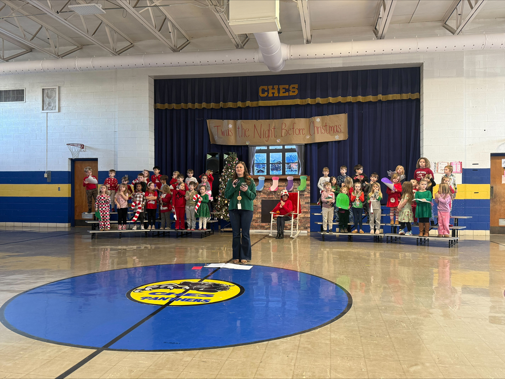 Mrs. Williams welcomes everyone to the Christmas program as students stand on risers behind her.
