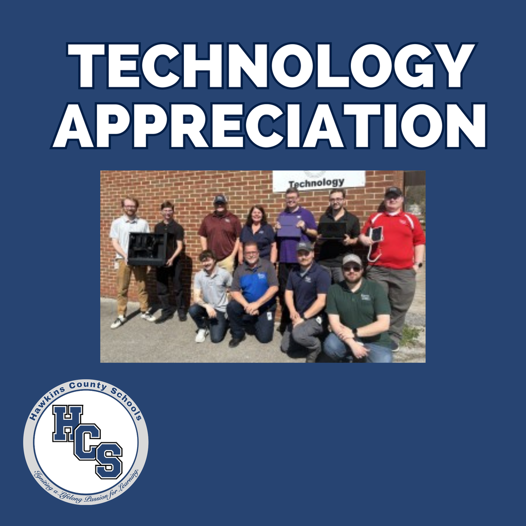 Group of people wearing casual clothes, some holding equipment, standing in front of a brick building.