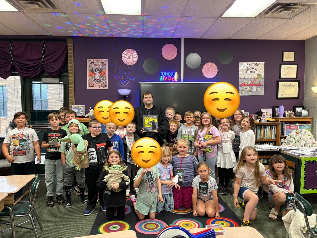 A classroom with purple walls and balloons with emojis. Children and adults are posing with smiles.